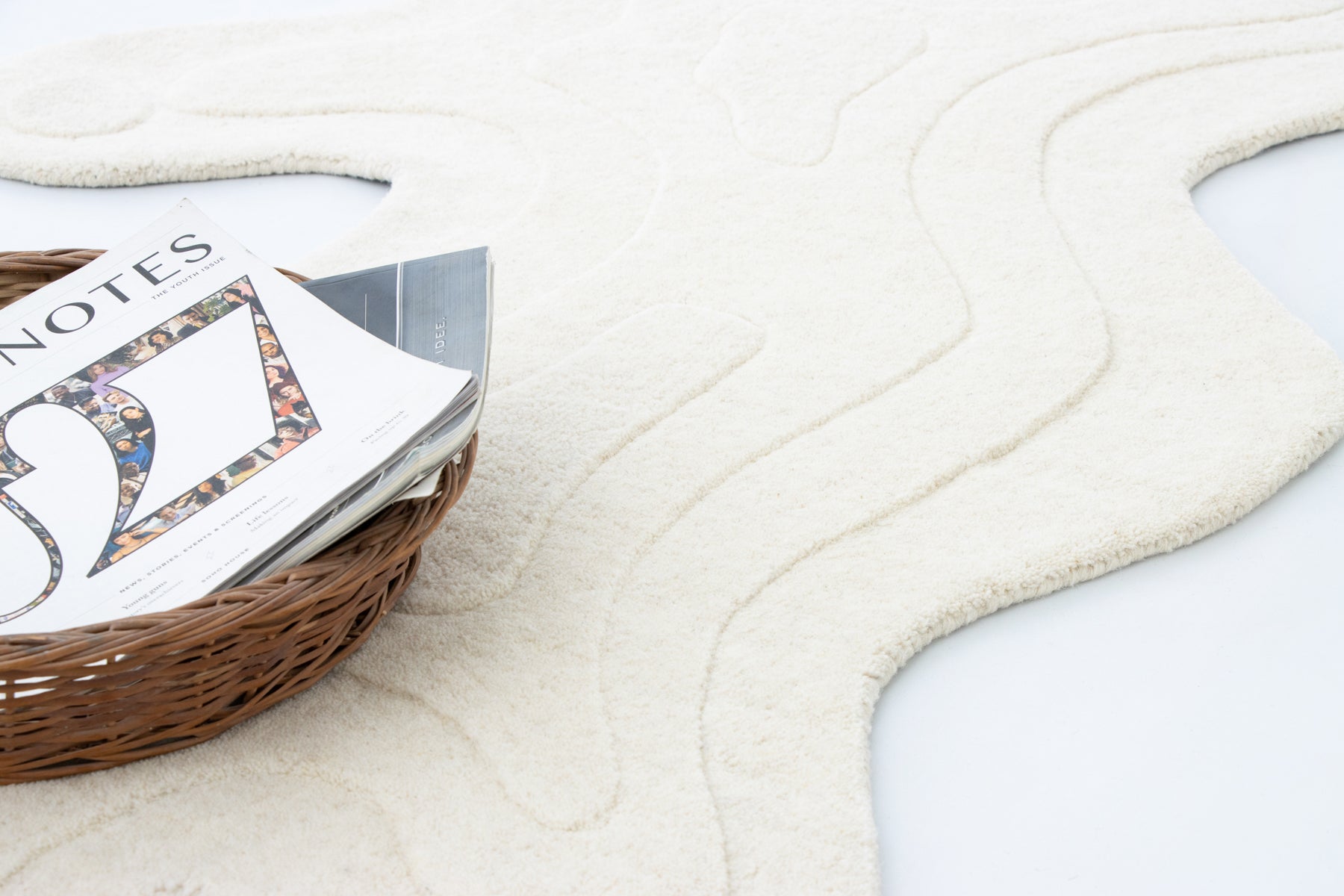 Amoeba Polar ivory rug angled shot with open book and woven basket