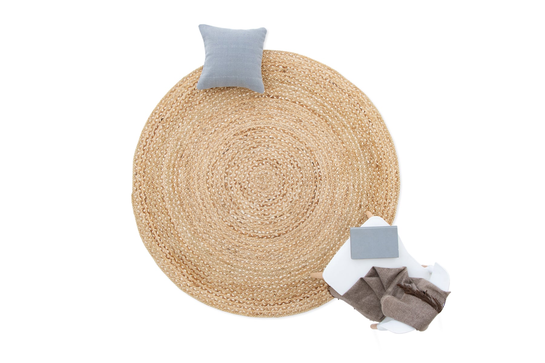 Round woven mat with a pillow and fabric pieces on a white background