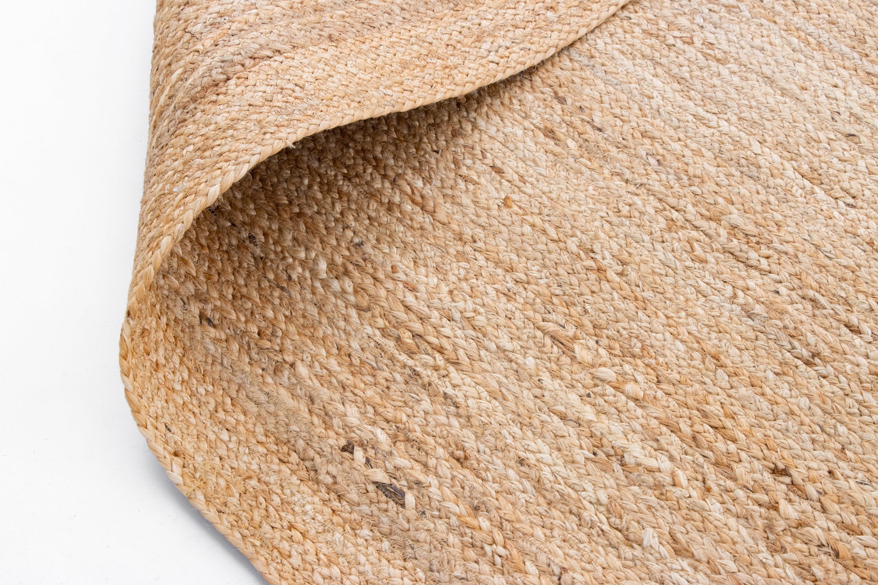Close-up of a woven jute rug on a plain background.