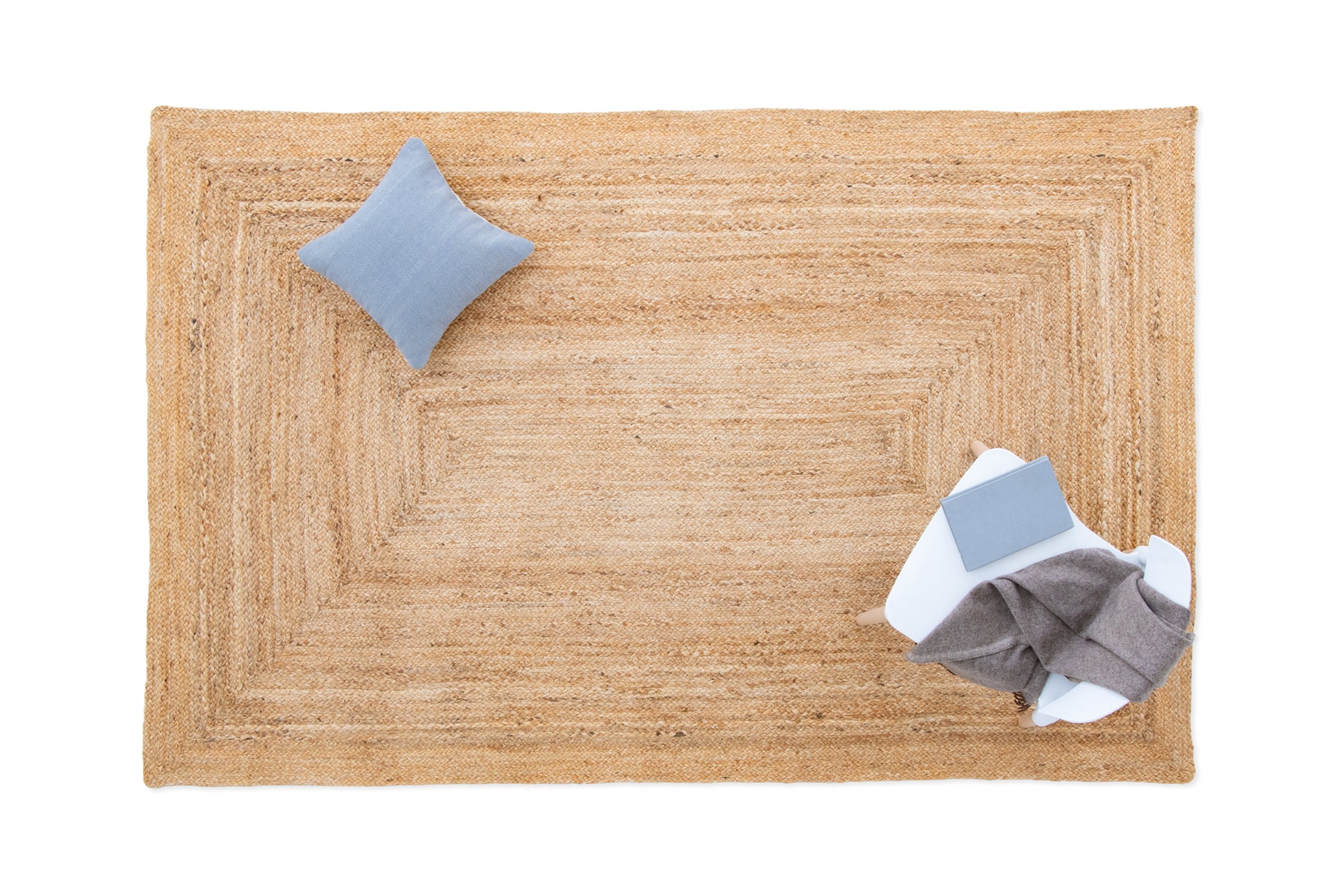 Beige rug with a blue pillow and gray clothing on a white background