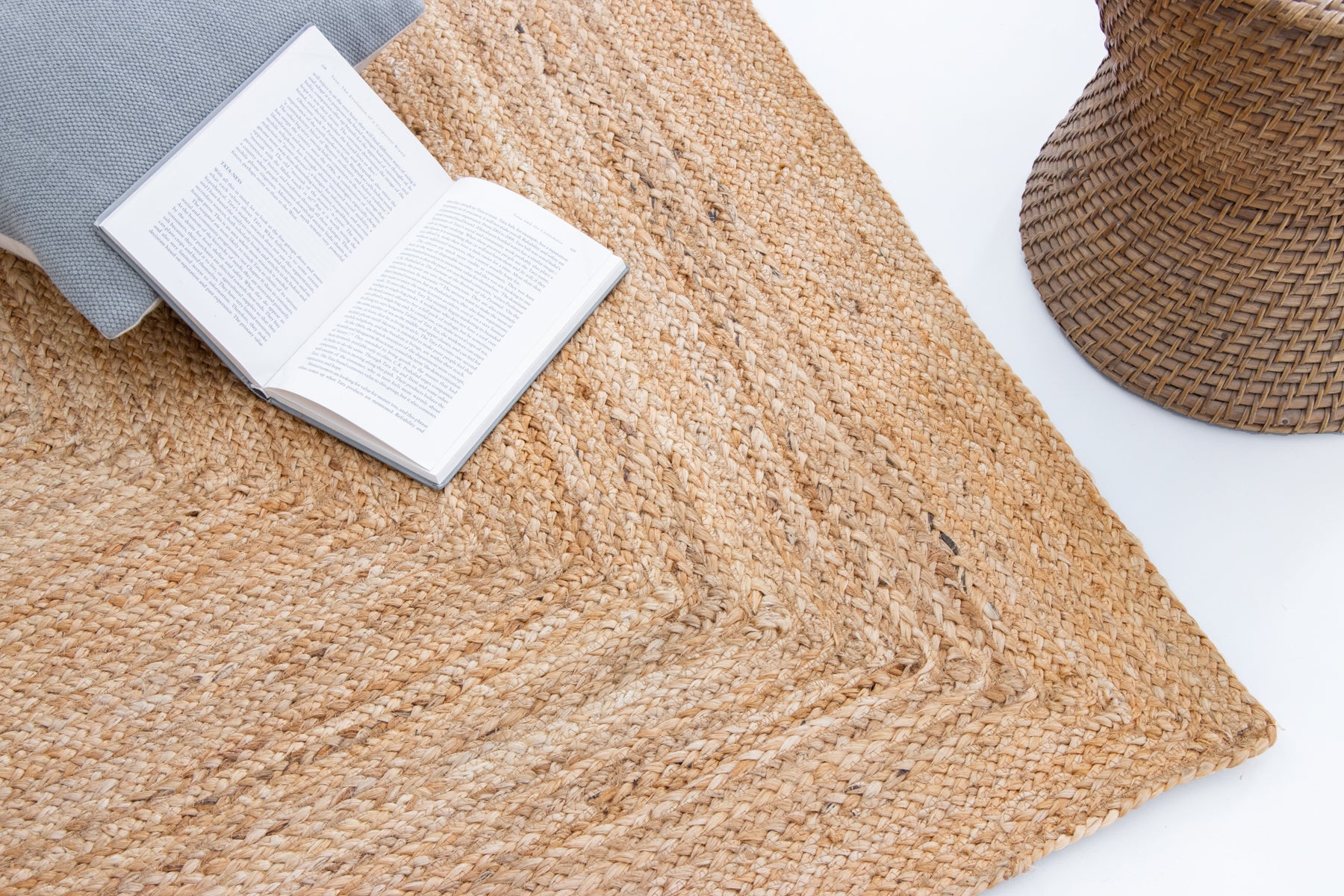 Open book and straw hat on a woven mat.