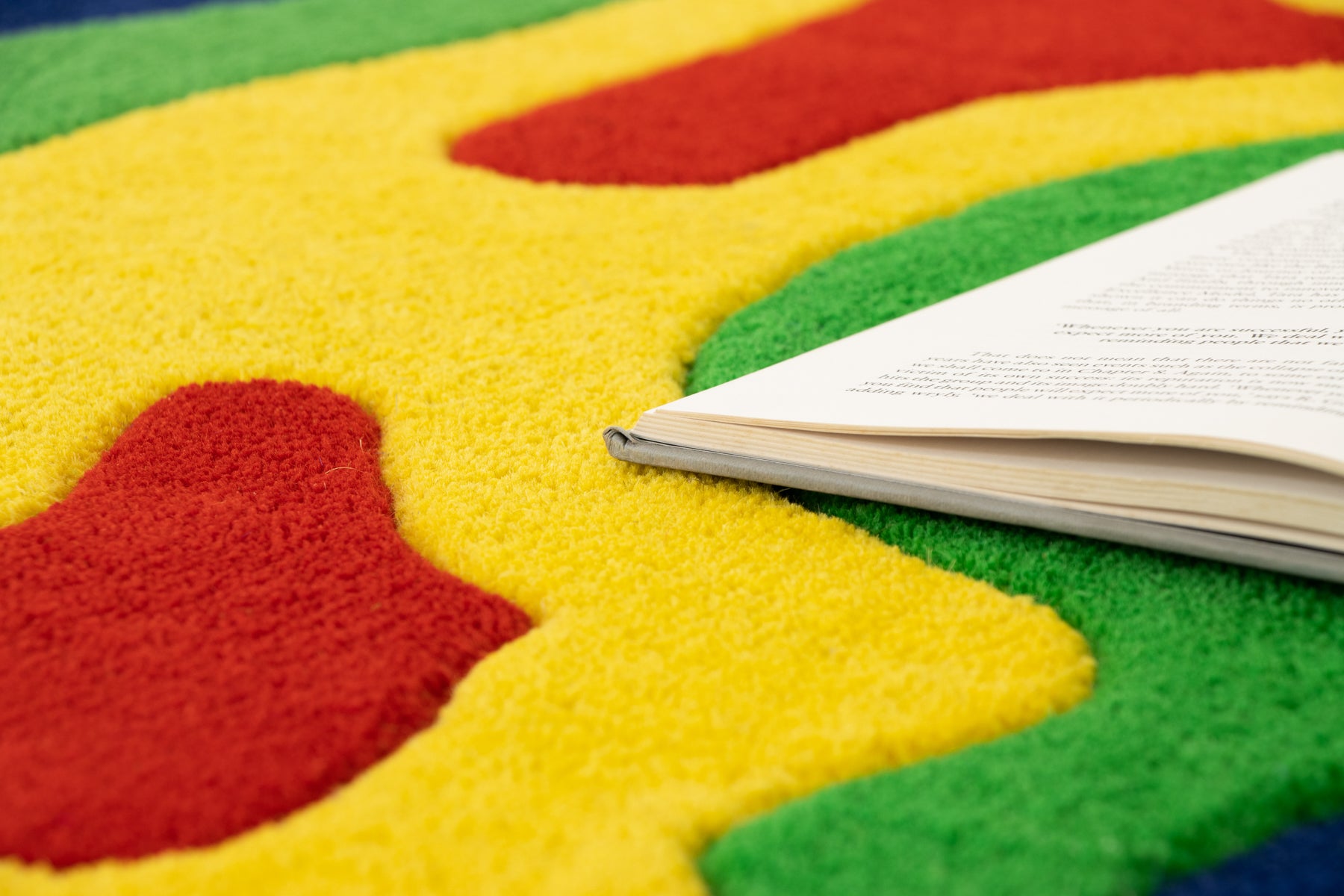 Amoeba Thermal rug close-up with open book on bright yellow and red wool pile | Beyond Rugs
