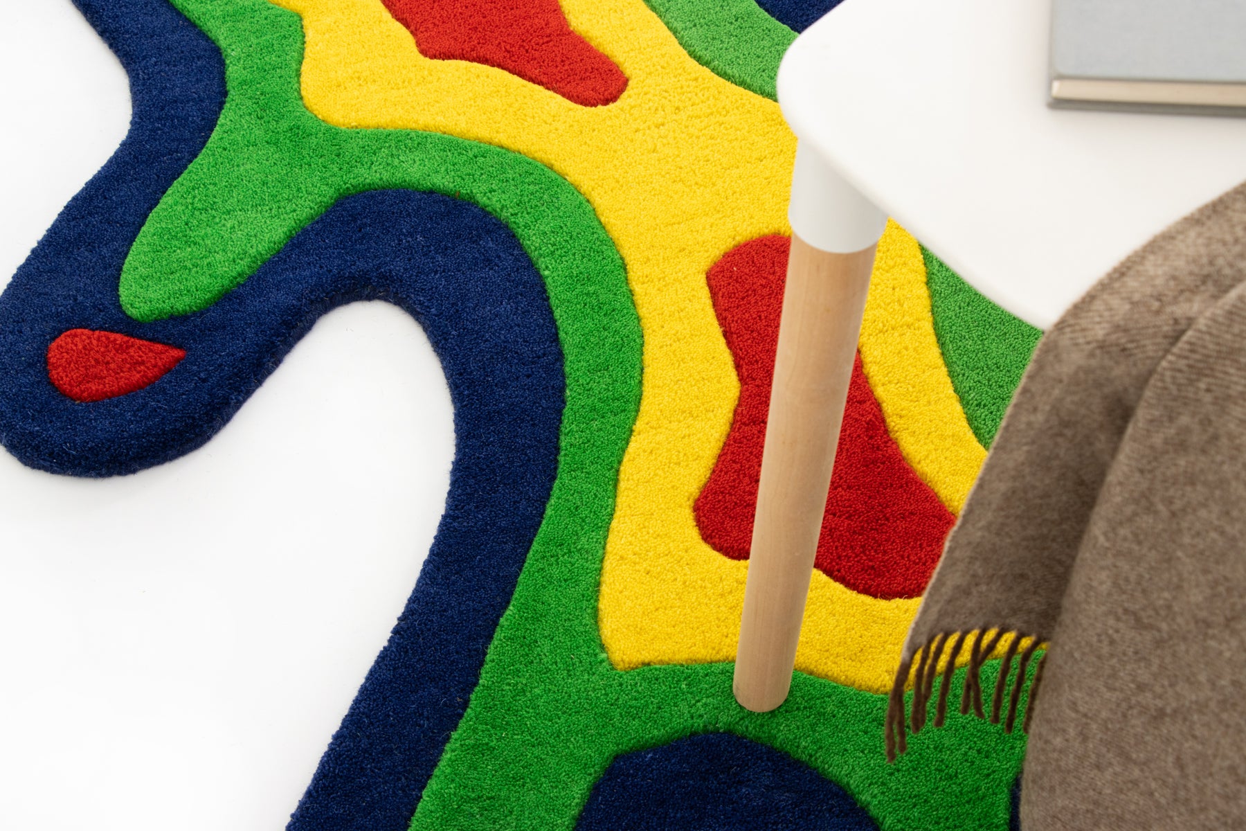 Amoeba Thermal rug upper section close-up against wall with stool and camel throw | Beyond Rugs