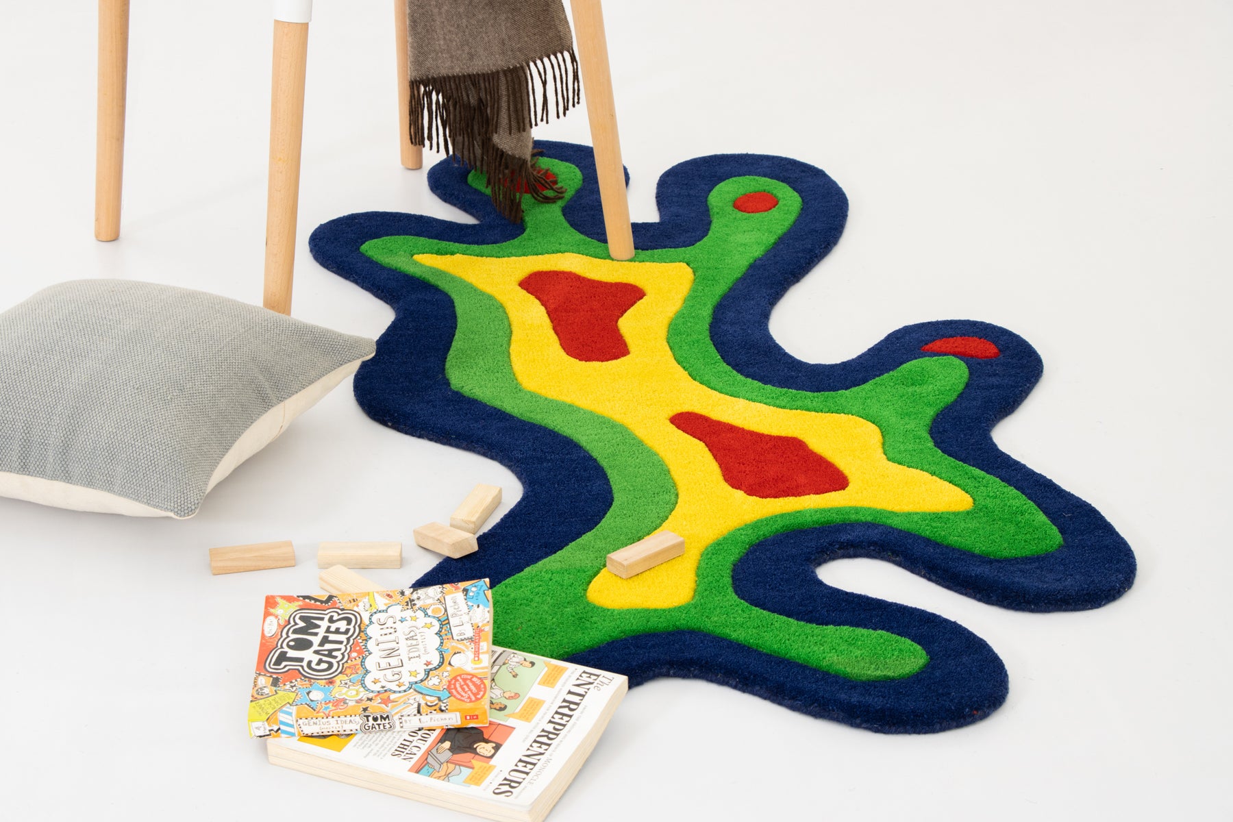 Amoeba Thermal rug wide aerial view with Jenga, coloring book, cushion and stool | Beyond Rugs