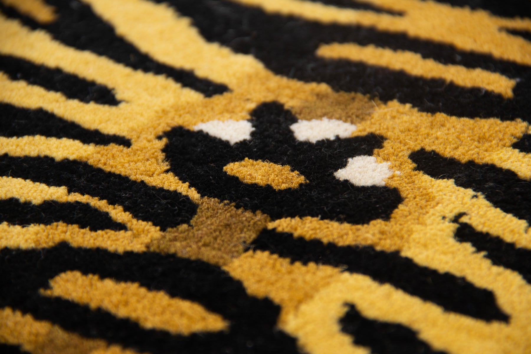 Close-up of bold black and golden tiger stripe pattern on hand tufted irregular wool rug | Beyond Rugs