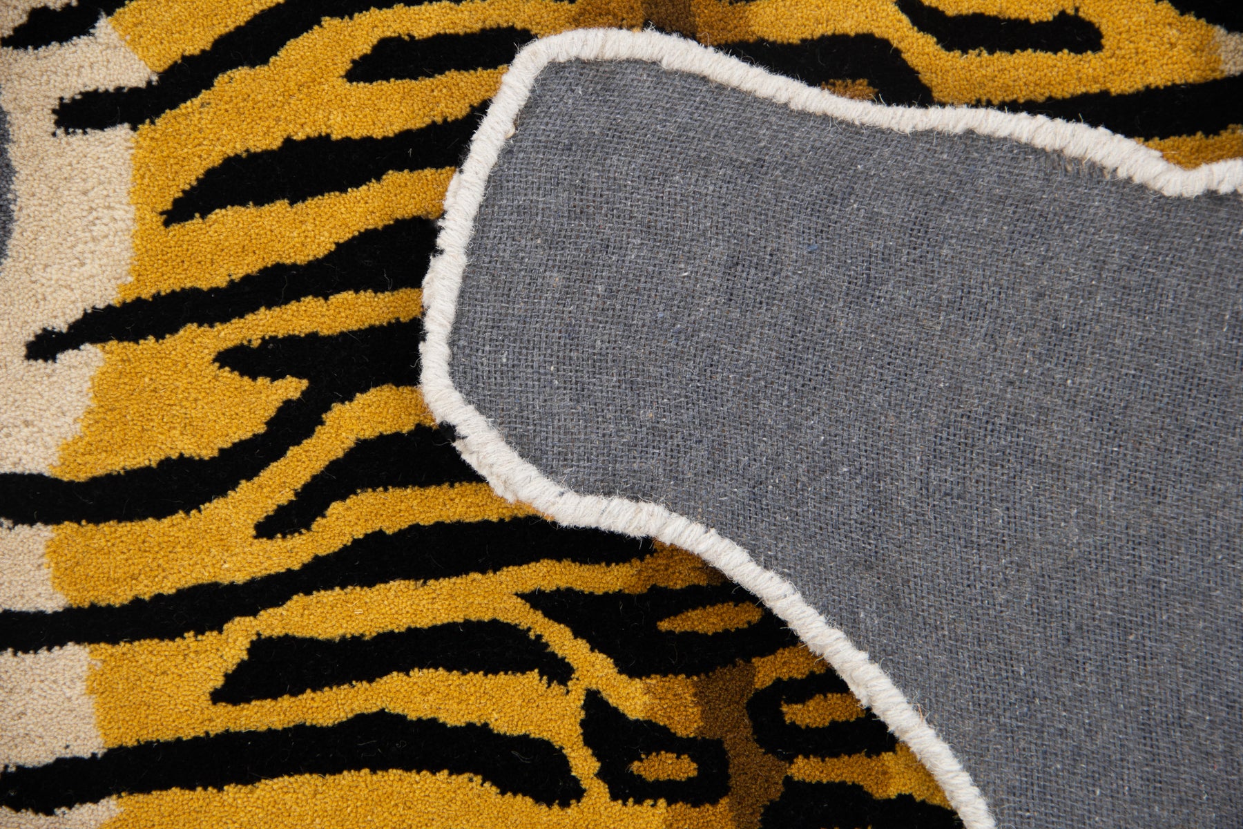 Back canvas view of classic tiger irregular rug showing grey lining and tiger silhouette edges | Beyond Rugs