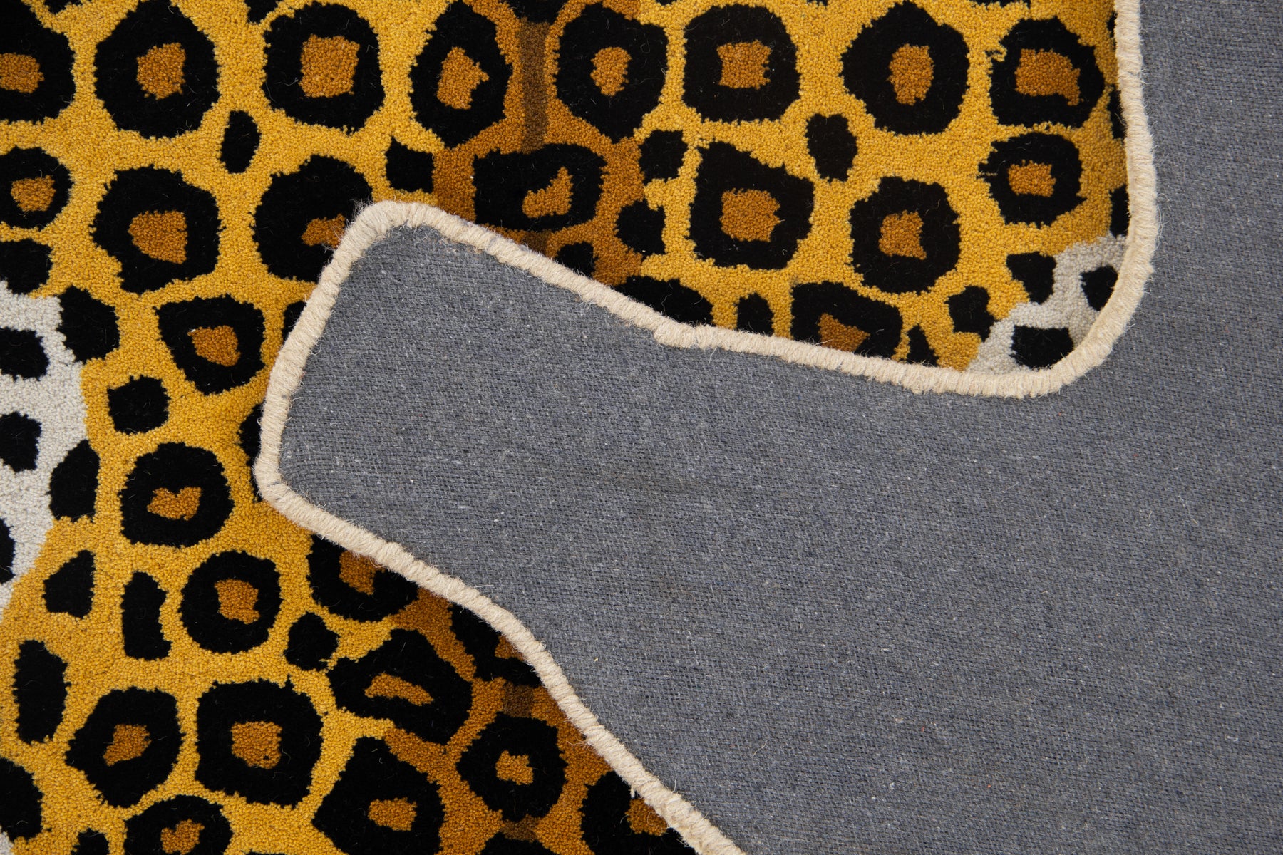 Back canvas of classic leopard irregular rug showing grey lining and animal silhouette edge | Beyond Rugs