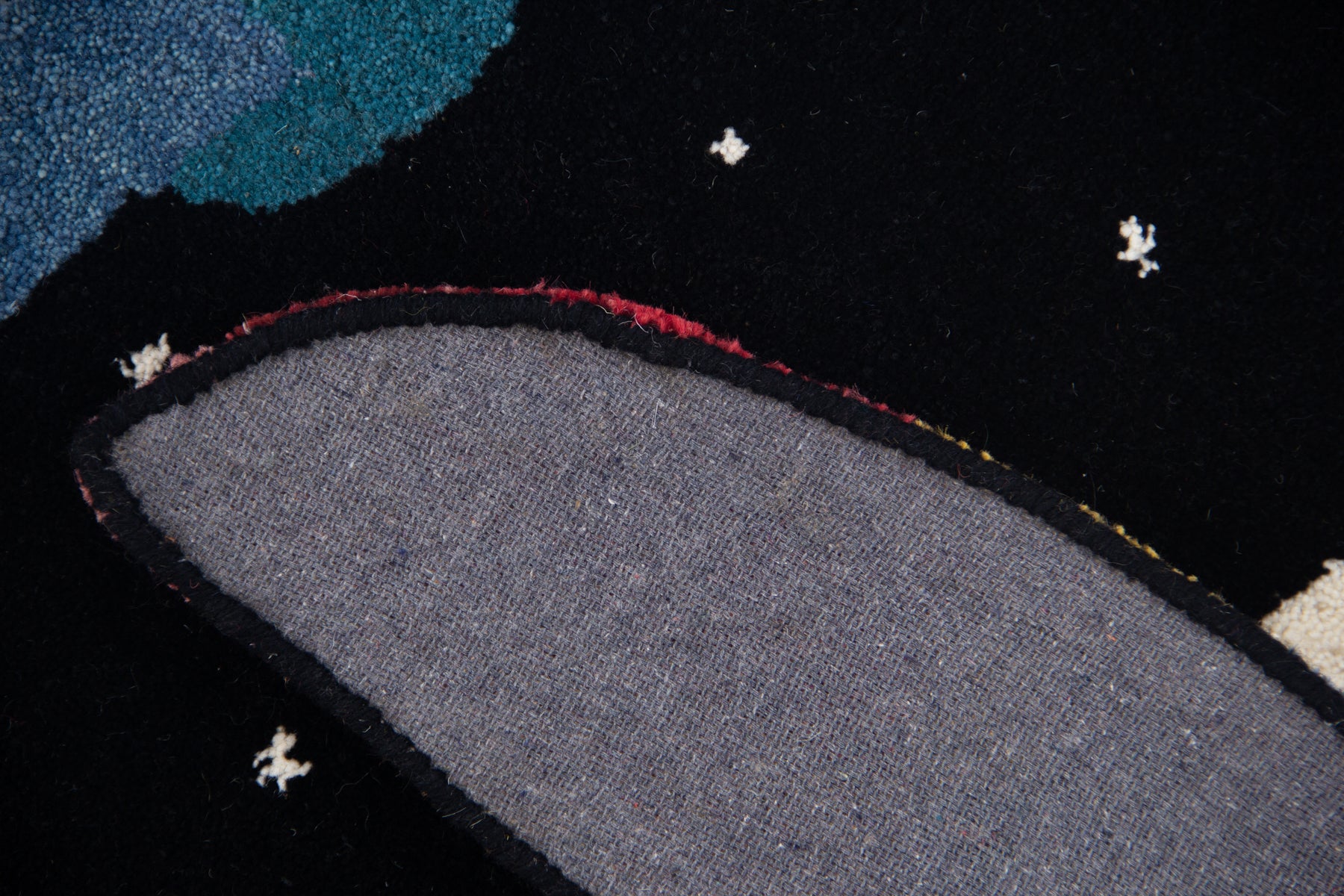 Back view of tropical toucan irregular rug showing grey canvas lining and cut-out shape | Beyond Rugs