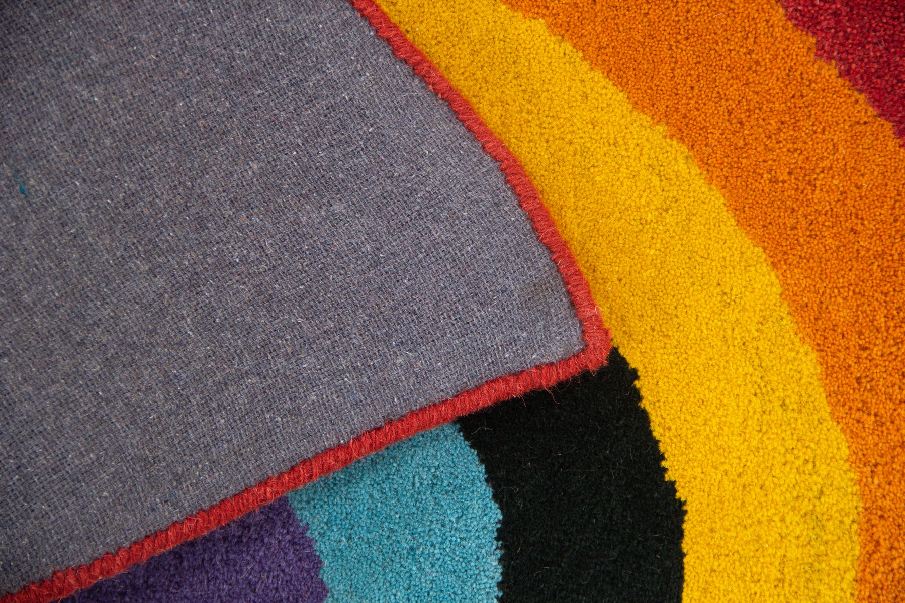 Back canvas of Cassata rainbow arch rug showing grey lining and multicolor cut-out edge | Beyond Rugs