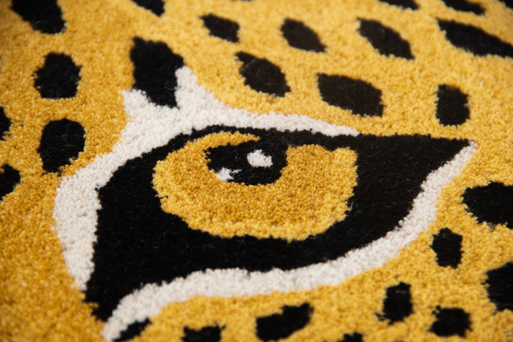 Close-up of leopard eye detail on golden yellow black circular irregular wool rug | Beyond Rugs