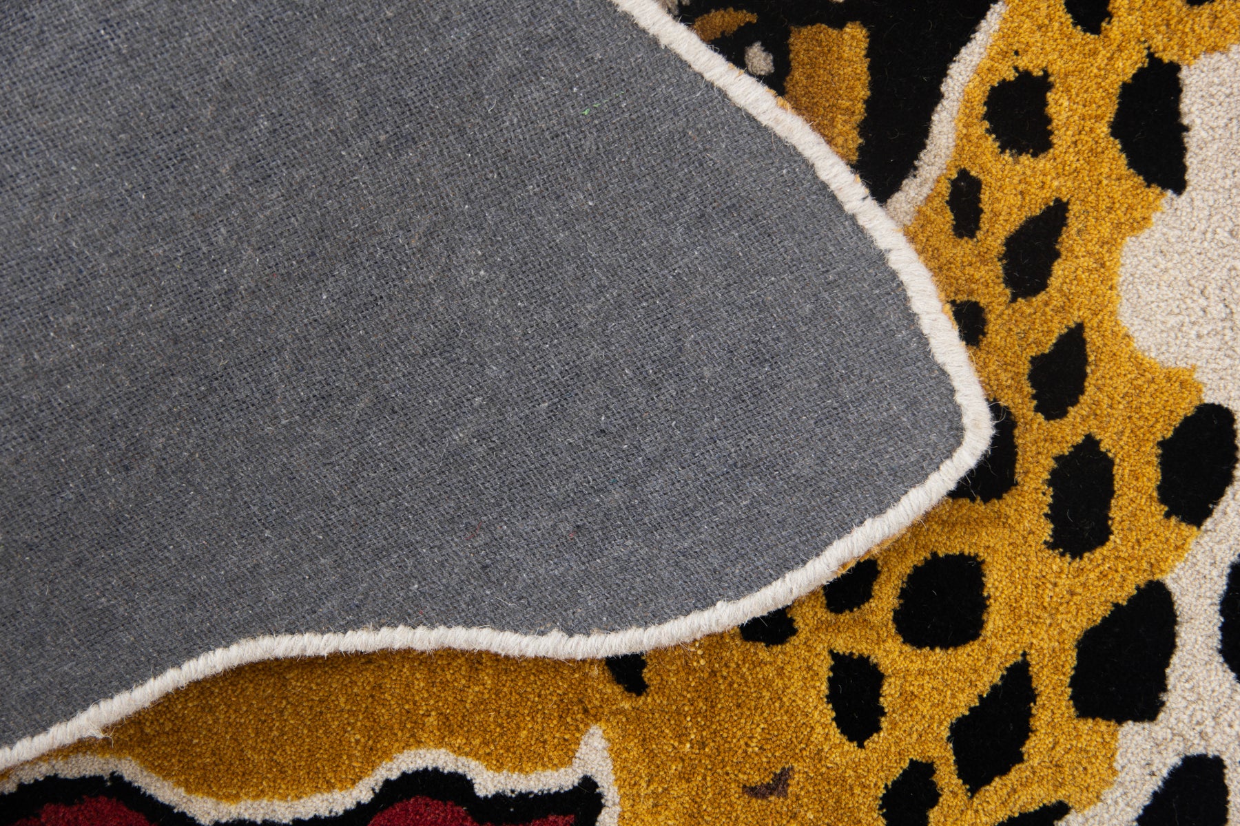 Back canvas view of golden yellow leopard circular rug showing irregular cut-out edge | Beyond Rugs
