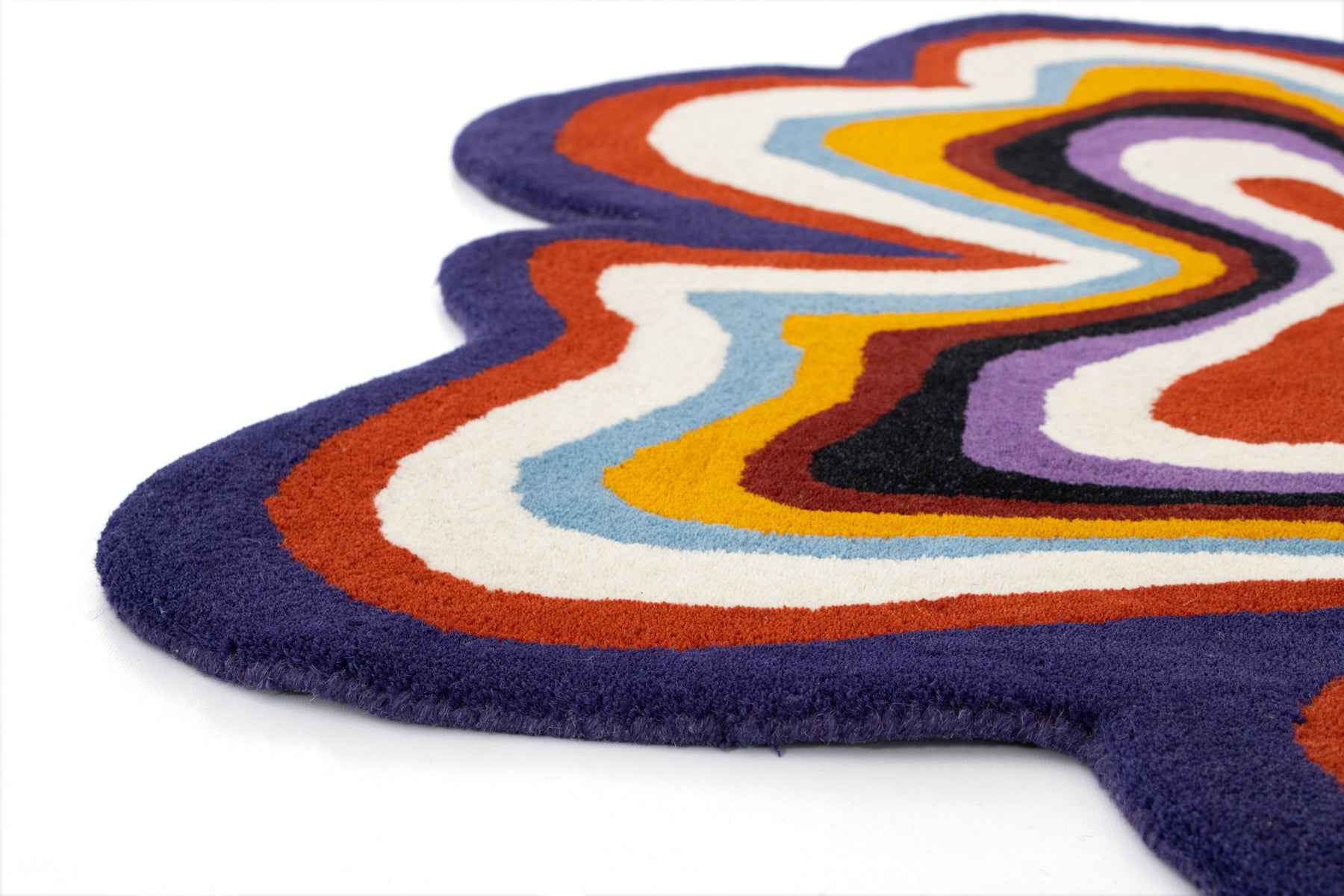 Side view edge detail of Paint Melts Radiant rug showing navy blue border and layered swirl pattern