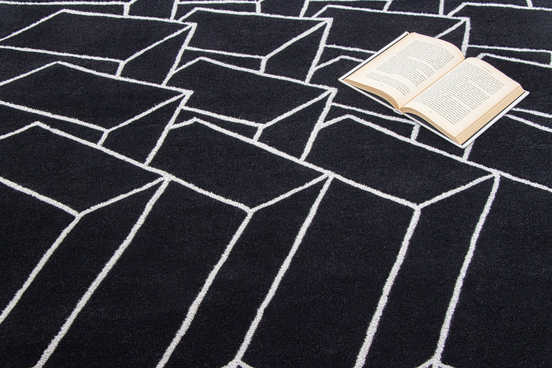 Open book on black irregular wool rug | Beyond Rugs USA
