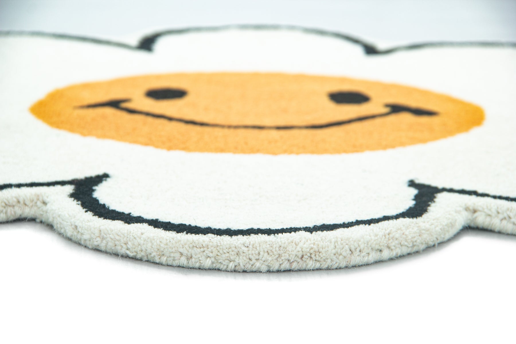 Side angle of white daisy flower emoji wool rug showing irregular petal silhouette edge | Beyond Rugs