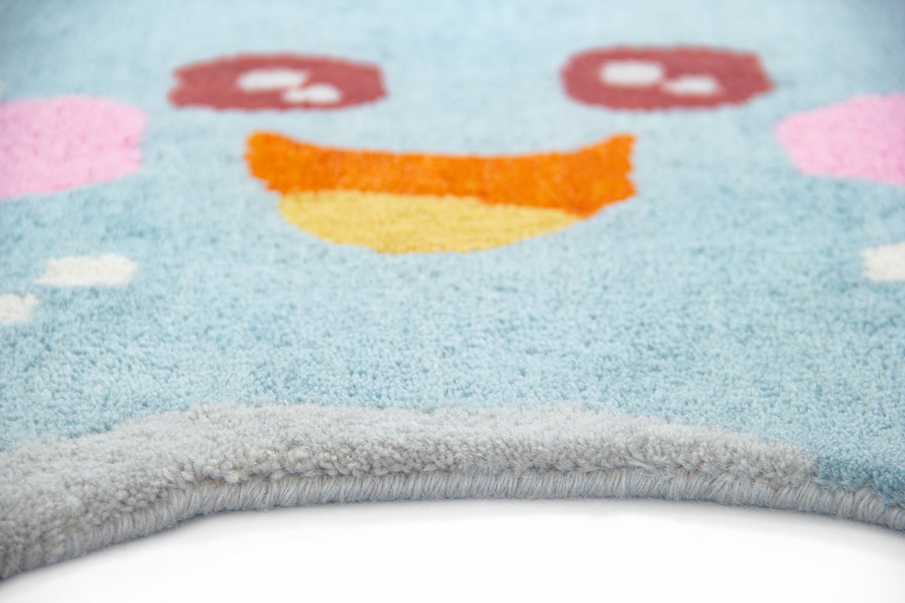 Angled view of baby blue starfish wool rug showing smiley face and irregular star edge | Beyond Rugs